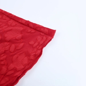 Dettaglio del vestito rosso con spalle scoperte e trama jacquard floreale in rilievo