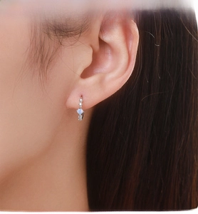 Close-up of S925 sterling silver hoop earring with opal stone and zircon on a model