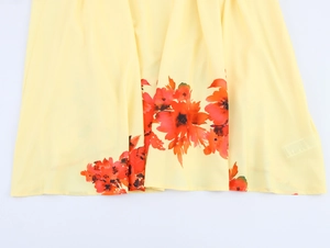 Detail eines eleganten Blumendrucks auf dem hellgelben Saum des Chiffonkleids