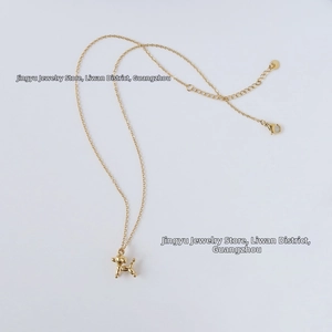 Macro detail of gold balloon dog pendant with lobster clasp and adjustable link chain