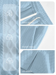 Detail view of waffle texture fabric, drawstring waist, and pockets on blue sports trousers