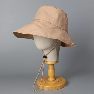 Détail du tissu du chapeau beige avec cordon coupe-vent réglable et étiquette de marque
