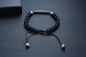 Makroaufnahme von schwarzem Onyx-Perlenarmband mit silberner Biegung auf Lederhintergrund