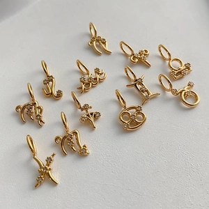 Primer plano de doce colgantes del zodiaco chapados en oro con circonitas para joyería DIY
