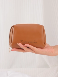 Macro detail of brown PU leather makeup pouch featuring gold zipper and star text print