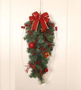 Red and green Christmas teardrop swag with ornaments and bow on a white front door
