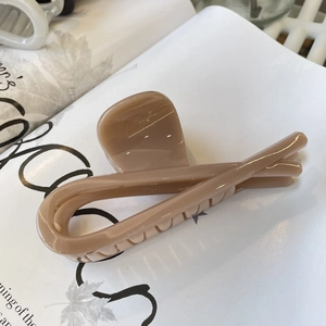 Detail view of large milk-tea colored hair claw clip on magazine background