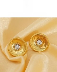 Macro view of gold-plated sunburst stud earrings with zircon on silk background