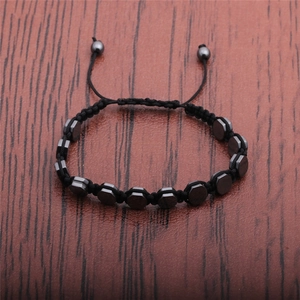 Detailed view of black braided rope bracelet with metallic hematite hexagonal beads