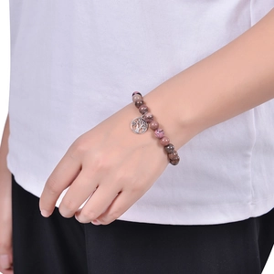 Detail of beaded natural stone bracelet featuring a silver tree of life charm on wrist