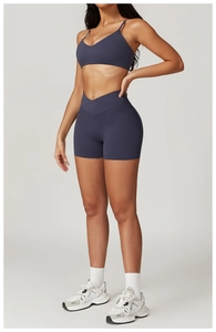 Detail of cross-waist high-waisted fitness shorts and V-neck sports top in dark grey blue