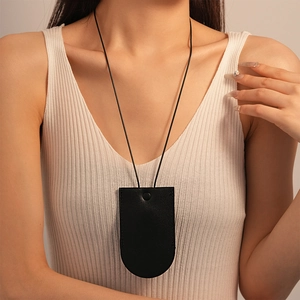 Detail of a minimalist black faux leather neck pouch with snap button and thin strap