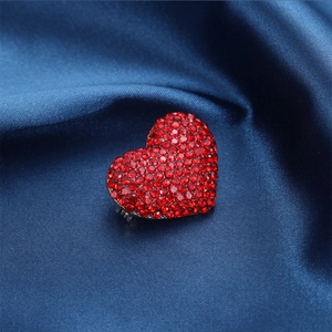 Detailed view of red rhinestone heart brooch on dark blue silk satin fabric