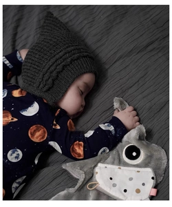 Close-up of a sleeping baby with a bear plush toy on a textured grey blanket