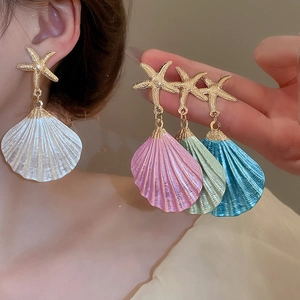 Detail view of colorful shell starfish earrings in white pink green and blue colors