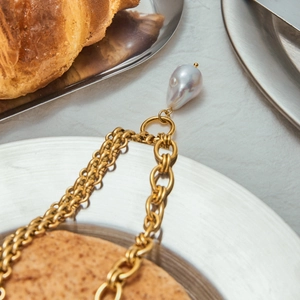 Elegant gold link chain necklace with a large baroque pearl pendant on metal plate
