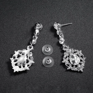 Close-up of silver drop earrings with pear-cut crystals and floral rhinestones