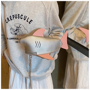 Detail of silver shark-shaped crossbody bag with pink fins and metal chain strap