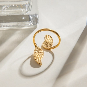 Detail of gold-plated wing ring featuring intricate feather textures on a textured surface