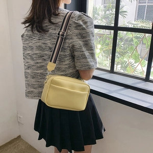 Chic lemon yellow crossbody square bag with contrast striped strap shown in lifestyle setting