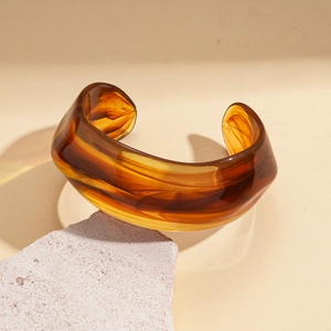 Macro detail of amber resin cuff bracelet with marble texture on stone platform