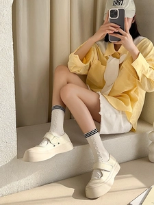 Detail of beige JK calf socks paired with Mary Janes and denim shorts in a preppy style