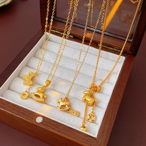 Detail of four gold plated necklaces with animal and horse pendants on wood jewelry box