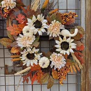 Close-up of autumn wreath featuring white pumpkins, sunflowers and rustic maple leaves