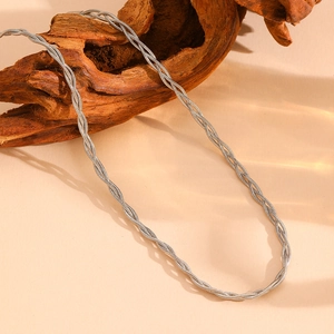 Macro shot of silver woven triple-layer stainless steel necklace on dark wood