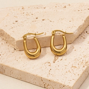 Macro shot of 18K gold-plated U-shaped hoop earrings on a textured stone surface