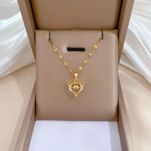 Detailed macro view of a gold fox pendant necklace with zircon on white silk background