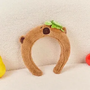 Detail of Capybara plush headband featuring a 3D green turtle on soft brown fleece fabric