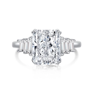 Macro shot of silver ring with emerald cut center stone and trapezoid side diamonds