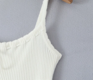 Gros plan sur la texture en maille côtelée blanche des bretelles et du décolleté