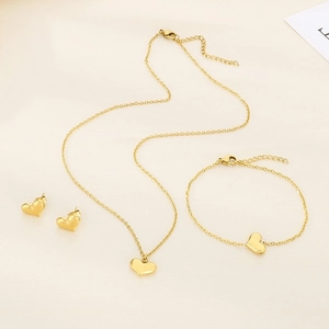 Detailed flat lay of 18K gold plated heart necklace, bracelet, and stud earrings set