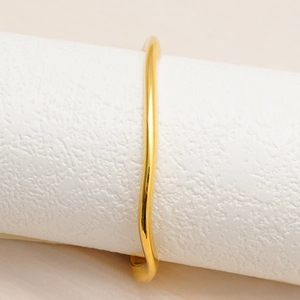 Dettaglio del design a onde irregolari su un bracciale a fascia minimalista placcato oro 18K