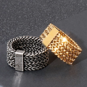 Hip hop style woven mesh chain rings in black and gold finish on textured surface