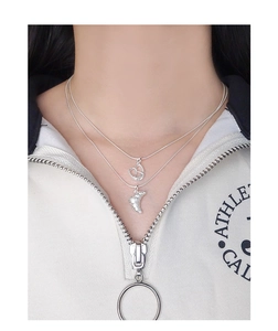 Close-up of layered silver heart and croissant pendants worn on a female model
