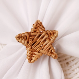 Macro shot of hand-woven rattan star napkin ring showing natural texture on white cloth