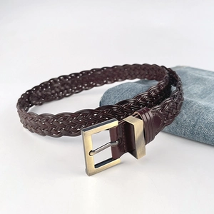 Hand-woven dark brown leather belt with metal buckle on casual jeans background