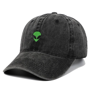 Dettaglio del ricamo verde della testa di alieno su un cappellino nero lavato