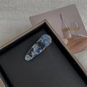 Detailed close-up of marble pattern teardrop hair clip in a black display box