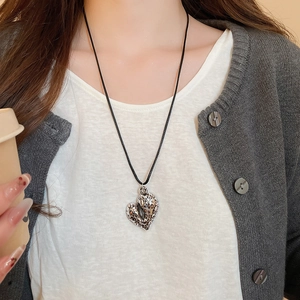 Close-up of lifestyle model wearing leopard print heart pendant on a black cord necklace