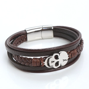 Detail of brown braided leather bracelet with silver skull charm and magnetic clasp