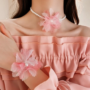 Detail of pink mesh flower choker and pearl bracelet set worn by a model
