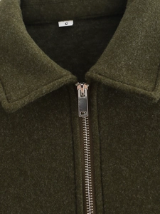 Detalle de chaqueta verde oliva con cremallera metálica y tejido con textura de lana