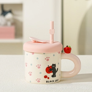 Close-up of cute ceramic cat mug with pink lid, straw, and small apple decoration