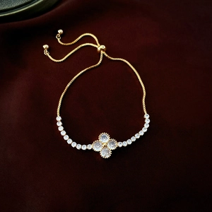 Macro detail of gold plated four-leaf clover bracelet with zircon crystals on velvet