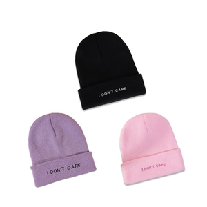 Three minimalist knit beanies in black, purple, and pink featuring I DON'T CARE embroidery