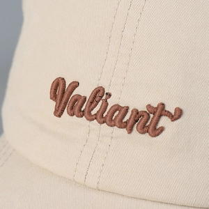 Detail van Valiant-borduurwerk op beige katoenen honkbalpet met luxe stiksels